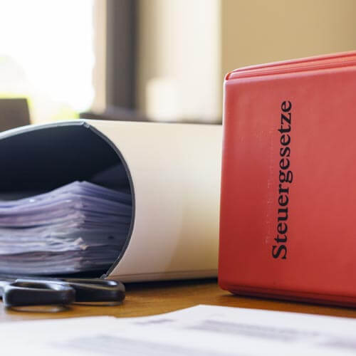 a red binder sitting on top of a desk next to a pile of papers