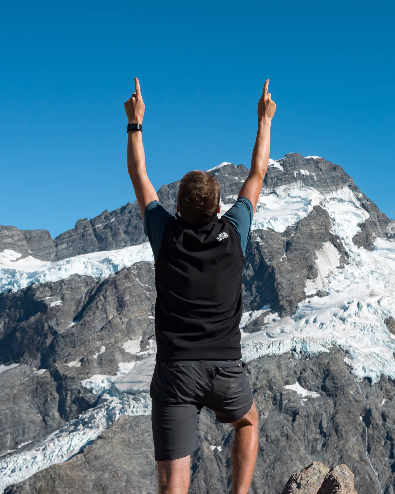 a man standing on top of a mountain with his arms in the air