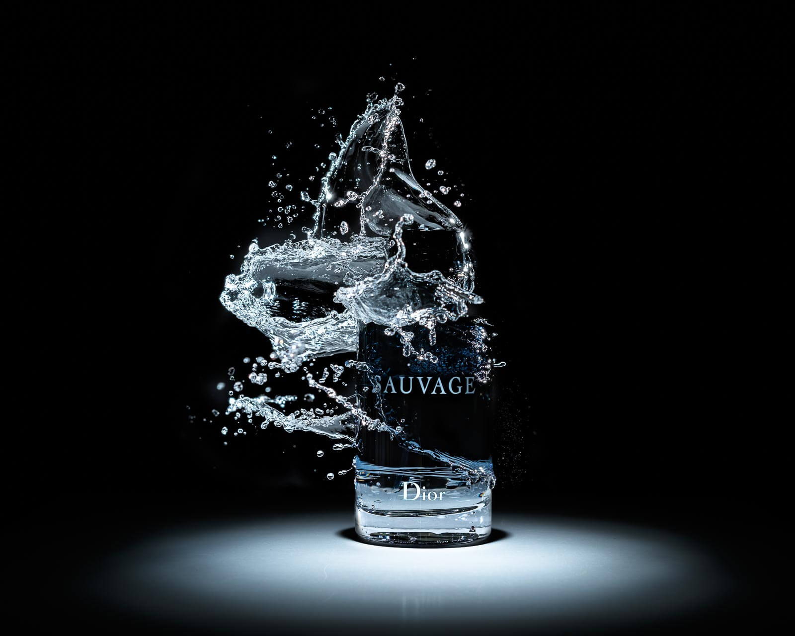 a bottle of perfume dior sauvage splashing into a glass