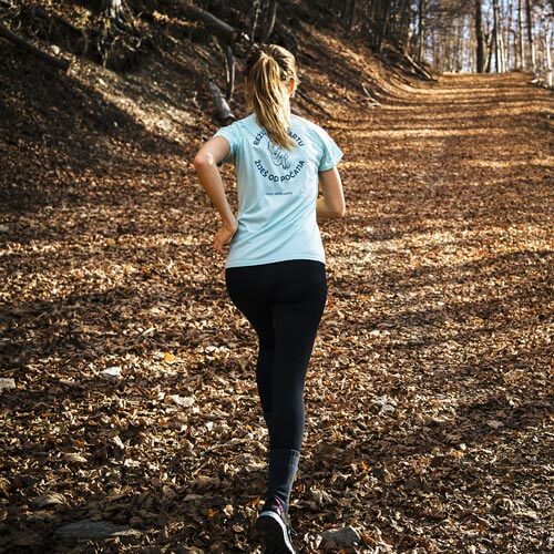 a woman is running on a trail in the woods