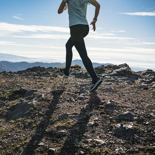 a woman is running on a rocky hill
